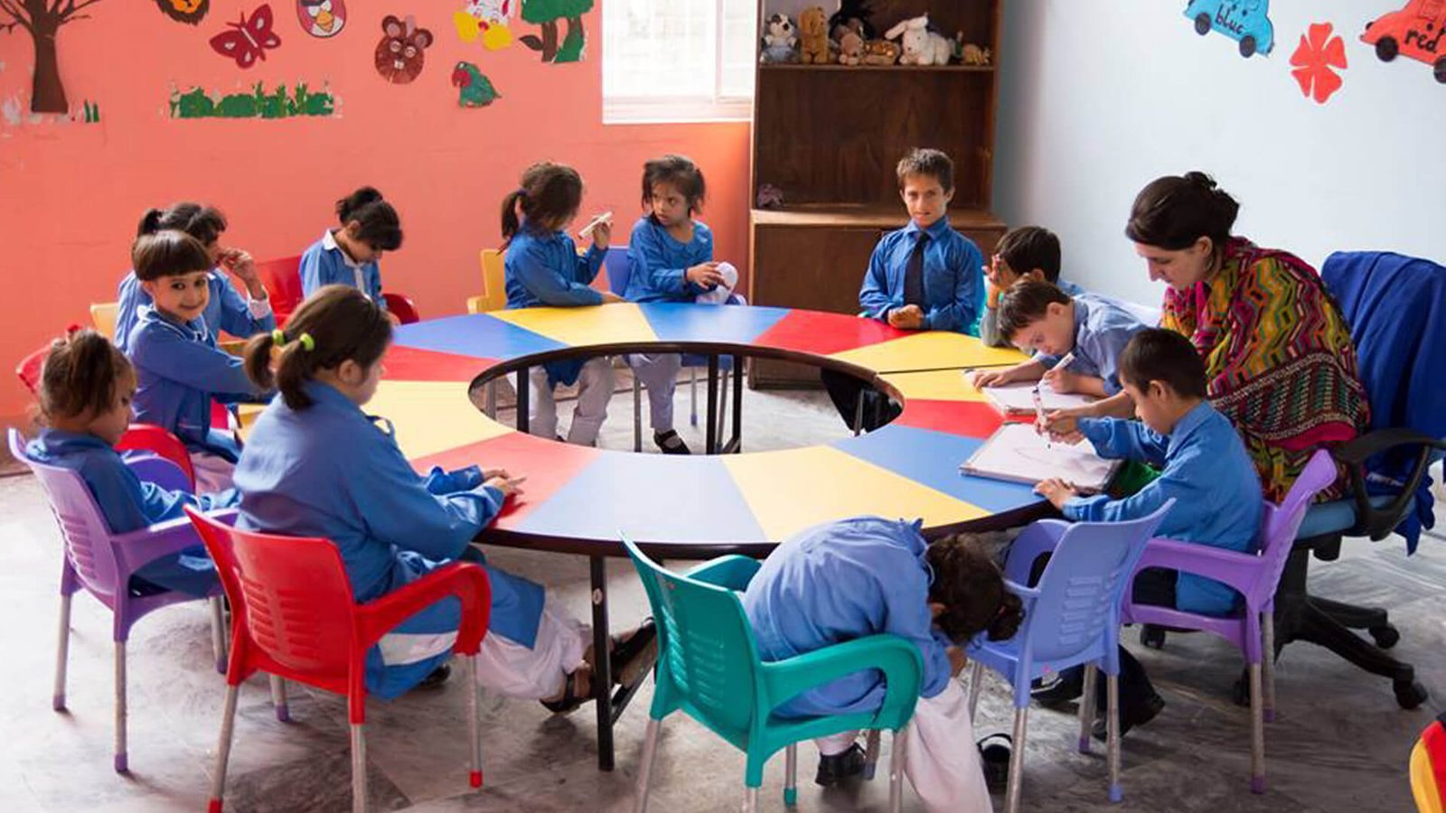 Children and a teacher learning together around a classroom table at Chambeli